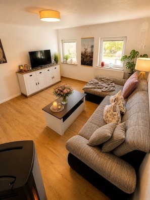 En moderne stue med sofa, sofabord, fjernsyn og billeder på væggene.