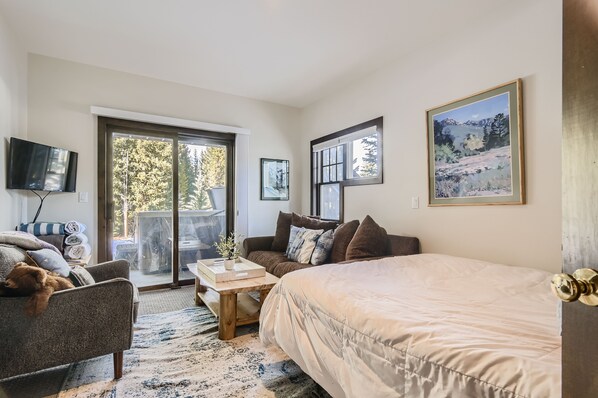 A modern bedroom with a large bed, a sofa, a coffee table, and a TV.
