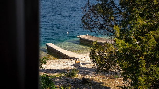Vista costera con agua cristalina, una costa rocosa y un muelle.