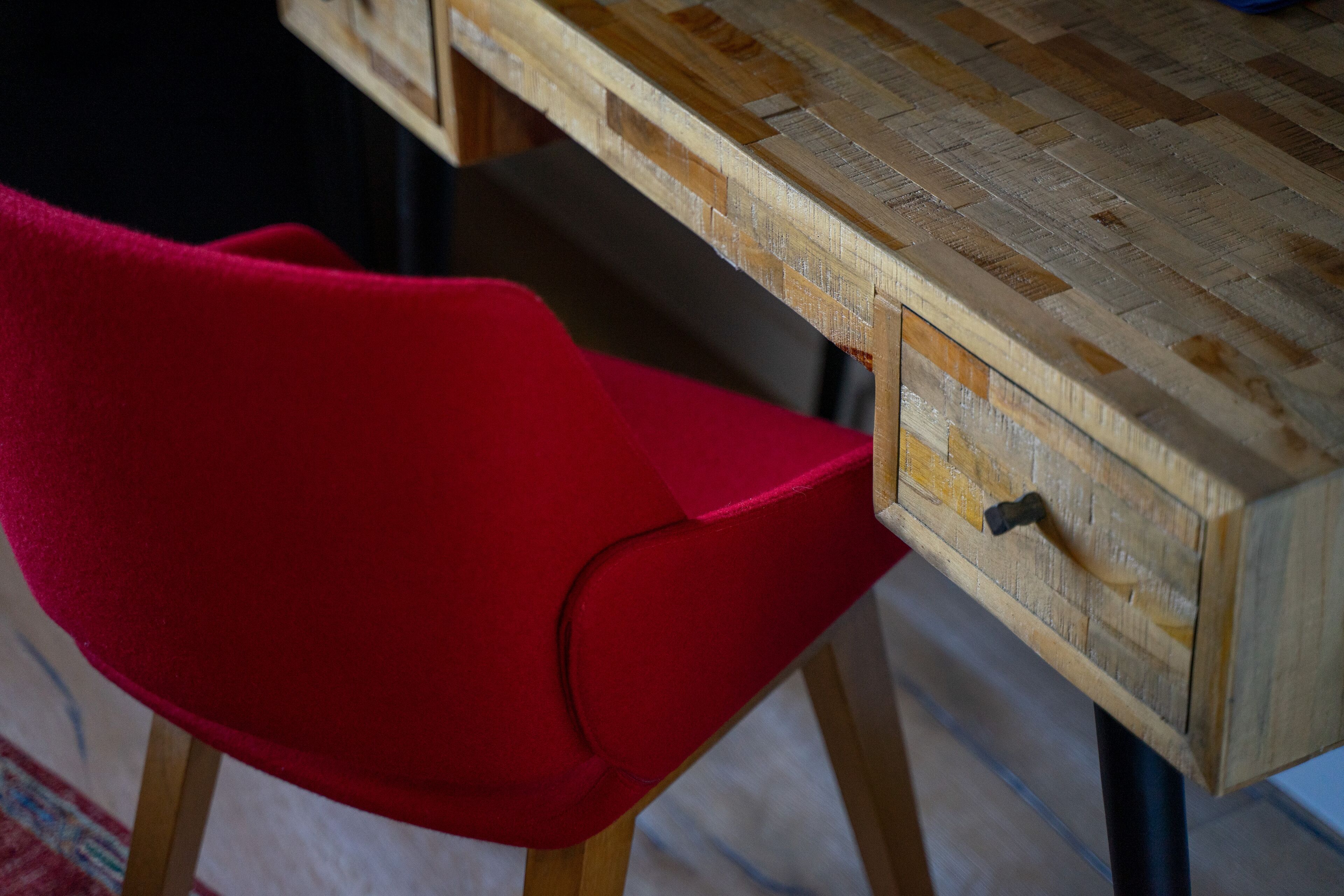 Ein Holztisch mit Schublade und ein roter Stuhl.