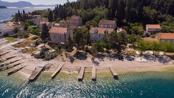 A coastal village with traditional stone buildings, a sandy beach, and boats docked near the shore.