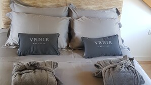 Una cama bien hecha con toallas y almohadones etiquetados como "VNRIK ARTS CLUB".