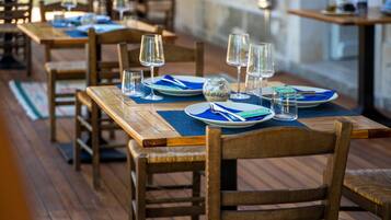 Un restaurante con mesas y sillas de madera, con platos, vasos y cubiertos colocados.