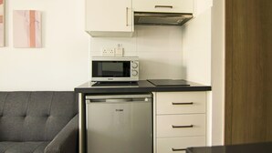 A compact kitchen with a microwave, a dishwasher, and a cabinet with a handle. - Phaedrus Living Seaside Flat Athina 115 (Paphos)
