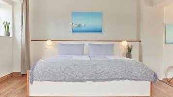 Una cama bien hecha con un edredón gris texturizado, dos almohadas y un cabecero con luces empotradas.