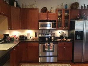 A kitchen with wooden cabinets, stainless steel appliances, a microwave, oven, and a refrigerator.