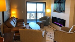 A living room with a sofa, armchairs, a coffee table, a fireplace, and a TV mounted on the wall. - Winter Paradise! NEW 2B/2B Walk to slopes Hot tubs (Snowshoe)