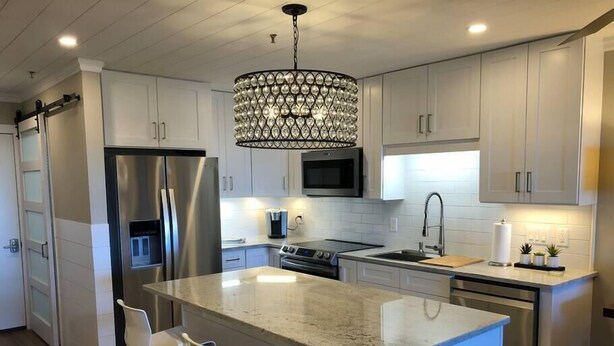 A modern kitchen with stainless steel appliances, a central island with bar stools, and pendant lighting. - Winter Paradise! NEW 2B/2B Walk to slopes Hot tubs (Snowshoe)