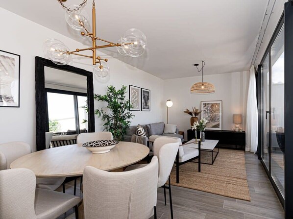 A modern dining area with a round table, chairs, and a chandelier.