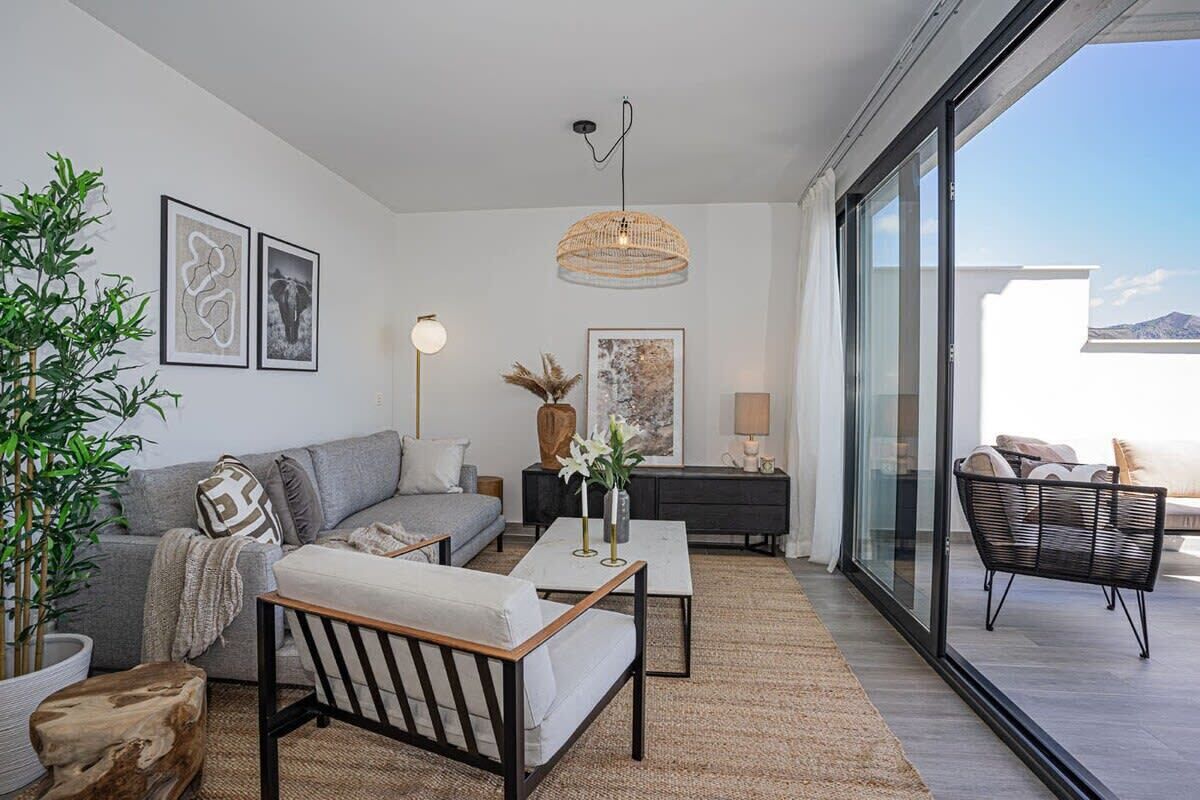 A modern living room with a sofa, coffee table, and a large window overlooking a balcony.