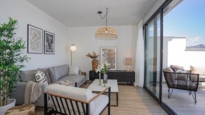 Ein modernes Wohnzimmer mit einer Couch, einem Couchtisch und einem großen Fenster mit Blick auf einen Balkon.