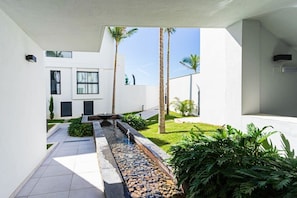 Un edificio moderno con fuente de agua, palmeras y un jardín bien cuidado.