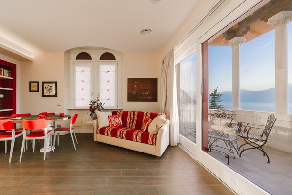 Un salon comprenant un canapé, une table à manger, des chaises et une grande fenêtre donnant sur un paysage montagneux.
