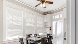 A dining area with a wooden table and chairs, white cabinets, and a ceiling fan. - Royal Resort (Jackson)
