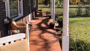 A covered porch with wicker furniture and a brick wall. - Although a country setting, the cottage has all modern conveniences & comforts (Climax)