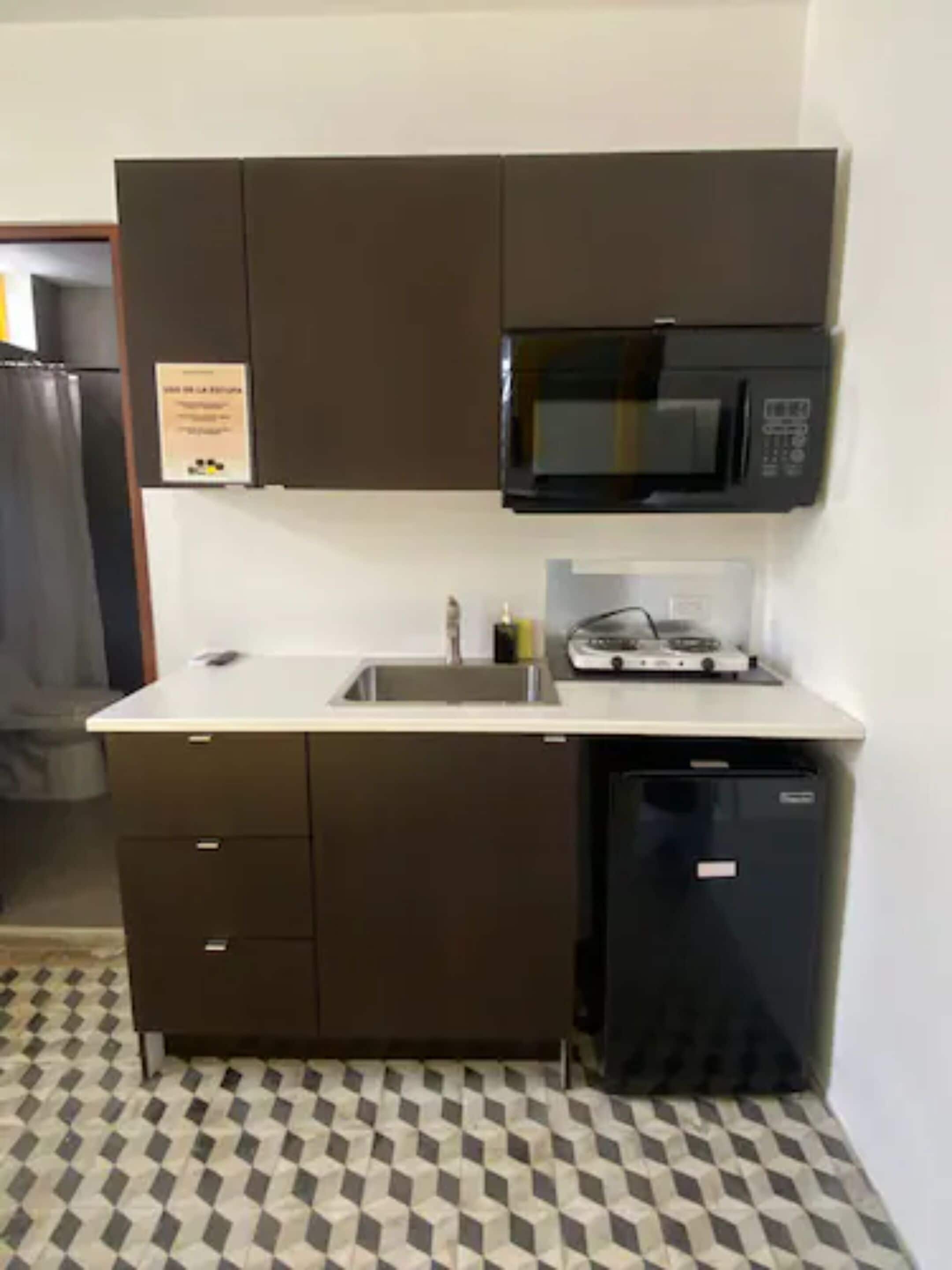 Una cocina compacta con microondas, fregadero y lavavajillas.