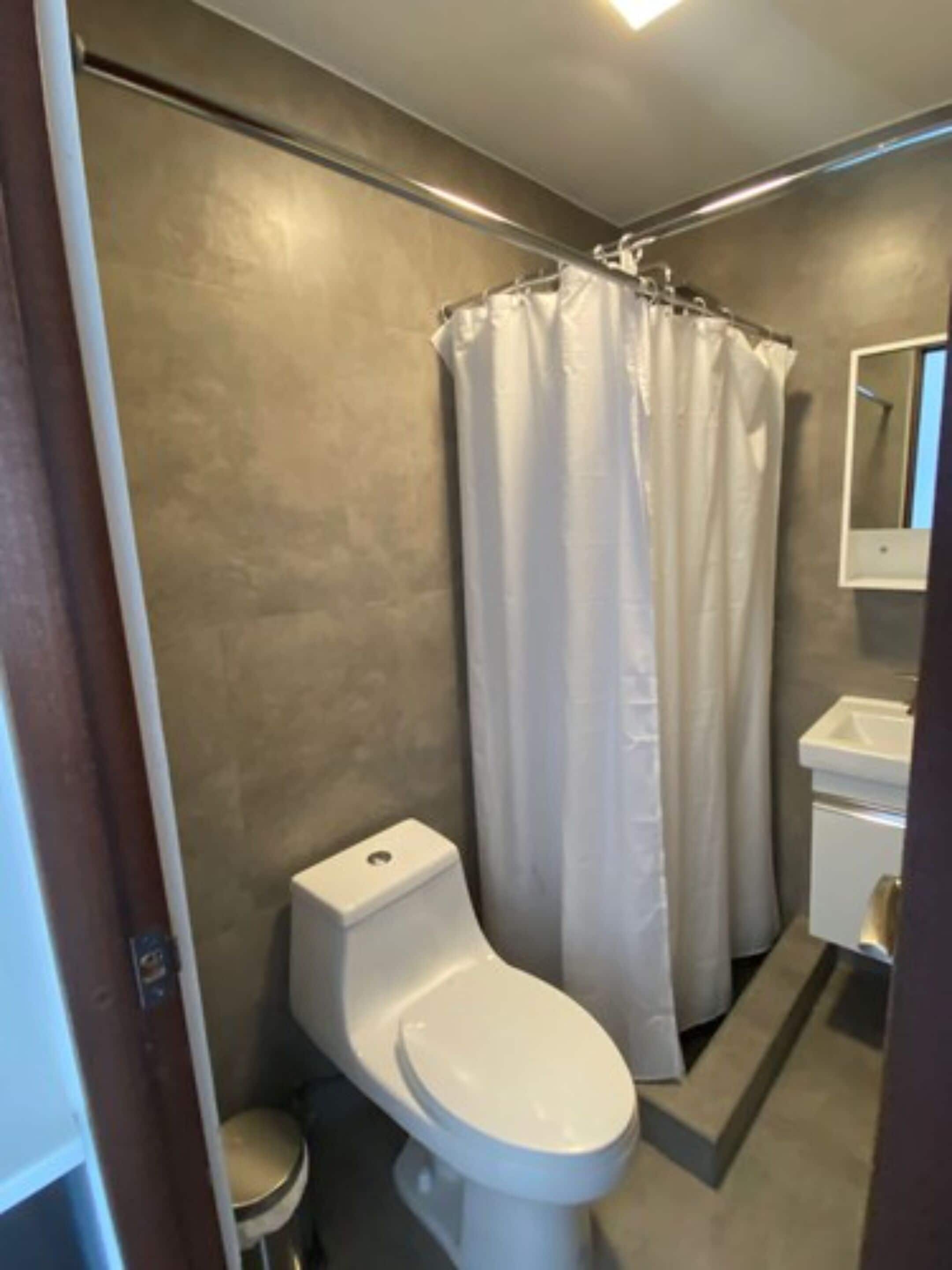 Un baño con inodoro, cortina de ducha y lavamanos.