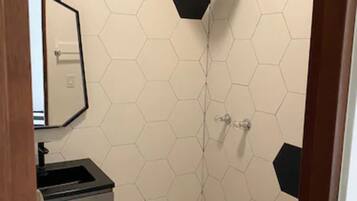 A bathroom with a hexagonal tile pattern, a toilet, a sink, and a shower.