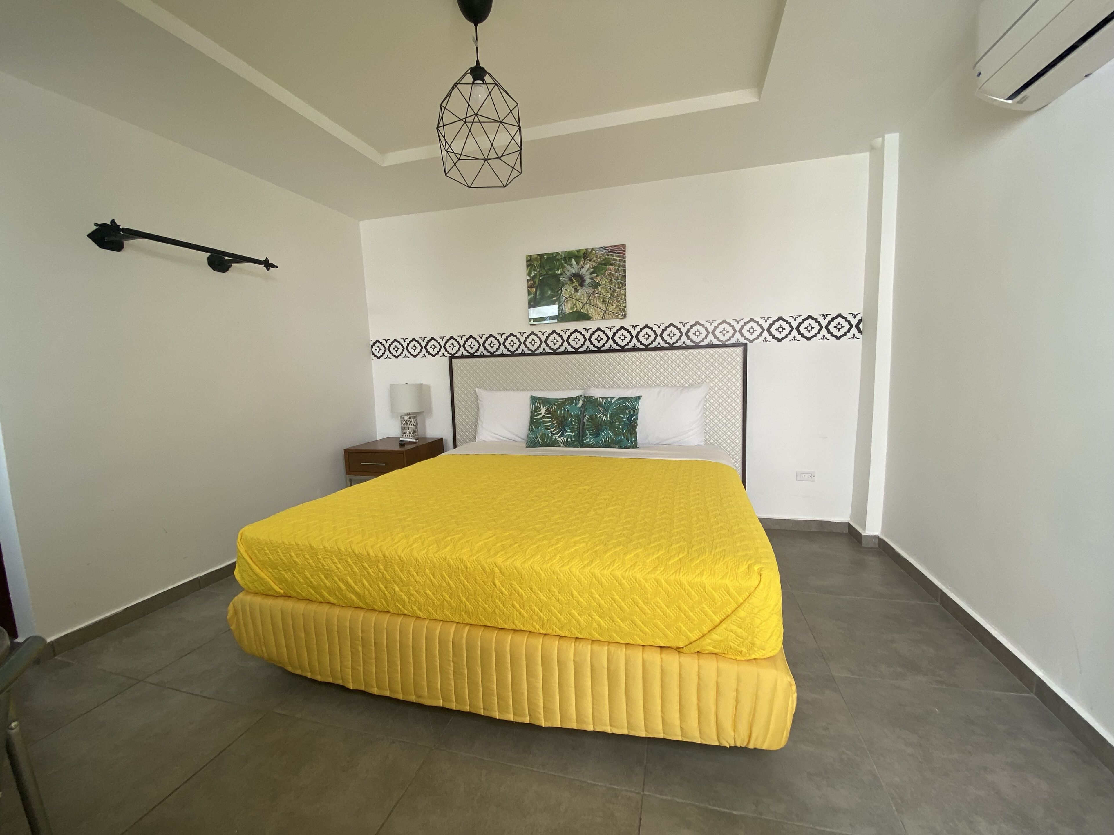 Un dormitorio con una cama grande, una mesita de noche, una lámpara de pared y un ventilador de techo.