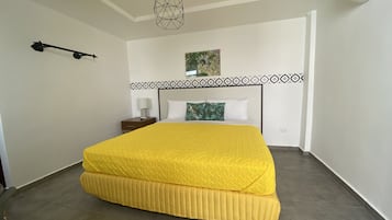 Un dormitorio con una cama grande, una mesita de noche, una lámpara de pared y un ventilador de techo.