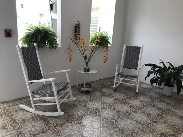 A corner seating area with two rocking chairs, a small table, and potted plants. - Hotel Nest (San Juan)