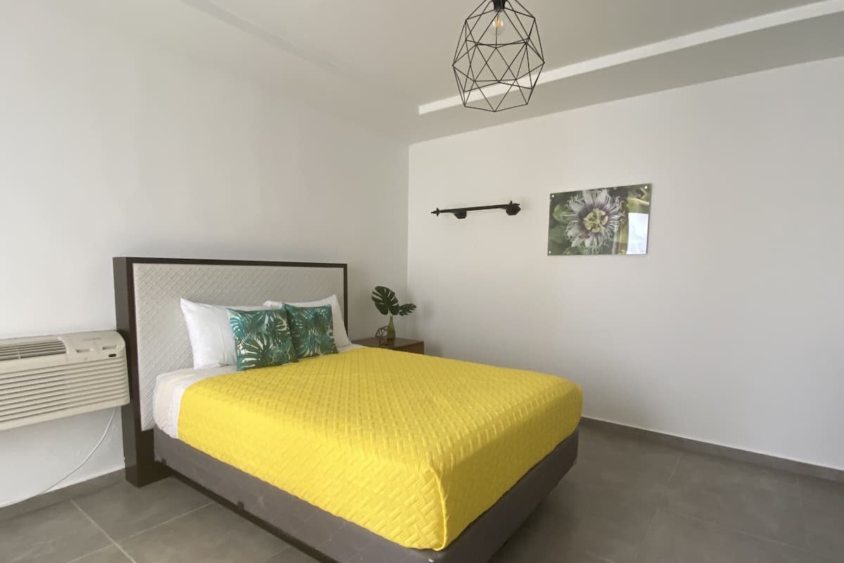 Une chambre à coucher moderne avec un lit, une table de chevet, un luminaire fixé au mur et un tableau encadré.