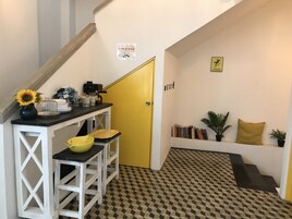 Una cocina con una puerta amarilla, una encimera blanca con un fregadero y un suelo estampado.