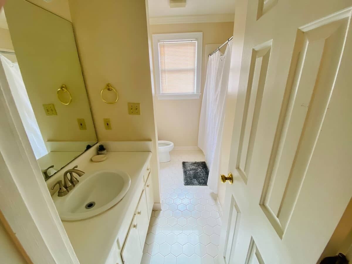 A bathroom with a white sink, mirror, and toilet.