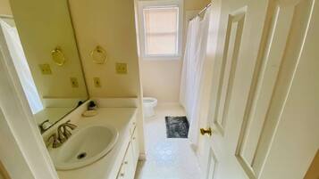 A bathroom with a white sink, mirror, and toilet.