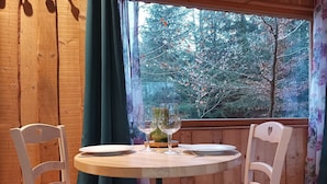 A wooden table with two chairs, a glass of wine, and a plate set for a meal.