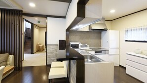 A modern kitchen with a central island, built-in appliances, and a staircase leading to an upper level. - HOTORI no TERRACE BAN (Fujikawaguchiko)