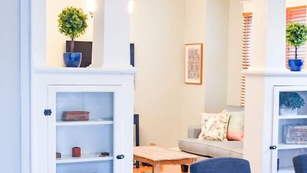 Een moderne woonkamer met een eethoek, met een houten vloer, een bank, een salontafel en een eettafel met stoelen.