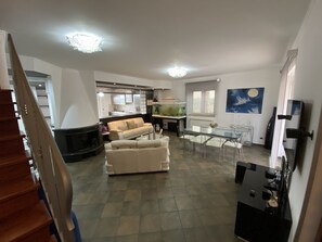A spacious living area with a sofa, dining table, and kitchen in the background.
