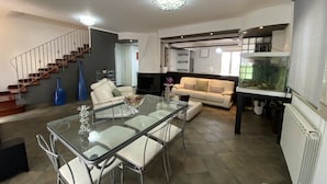 Ein modernes Wohnzimmer mit einem Glastisch, weißen Sofas, einer Treppe und einem Aquarium.