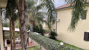Ein Innenhof mit Palmen, einer Terrassenfläche und einer Wand-Klimaanlage.