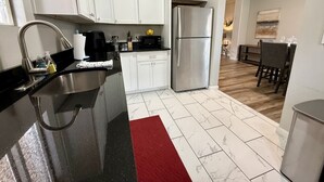Una cucina moderna con mobili bianchi, un frigorifero in acciaio inossidabile e un piano di lavoro nero.