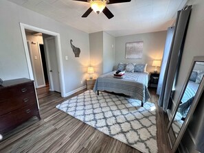 A bedroom with a bed, nightstands, a dresser, and a ceiling fan.