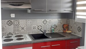 A kitchen with grey cabinets, a red countertop, a sink, a stove, and a washing machine. - 43 m² apartment with balcony, 80 m from Demoiselles beach, (Saint-Hilaire-de-Riez)