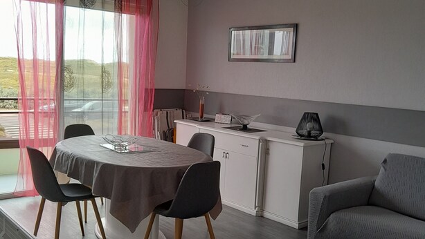 A modern living room with a dining area, grey sofa, and a white coffee table. - 43 m² apartment with balcony, 80 m from Demoiselles beach, (Saint-Hilaire-de-Riez)