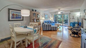 A modern living room with a dining area, a sofa set, and a kitchen area.