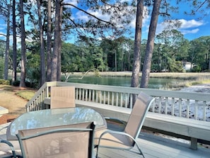 Une terrasse avec une table et des chaises donnant sur un lac, entourĂ©e dâarbres.