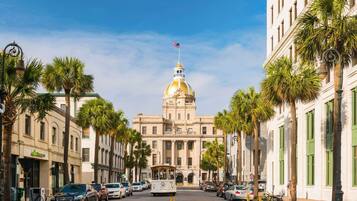 A street view with a prominent building featuring a large dome and an American flag.