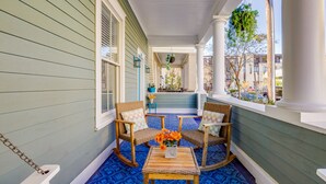 A porch with rocking chairs, a small table with a vase of flowers, and a blue patterned floor. - ⭐Southern Charmer•Historic Downtown•Private Porch⭐ (Savannah)