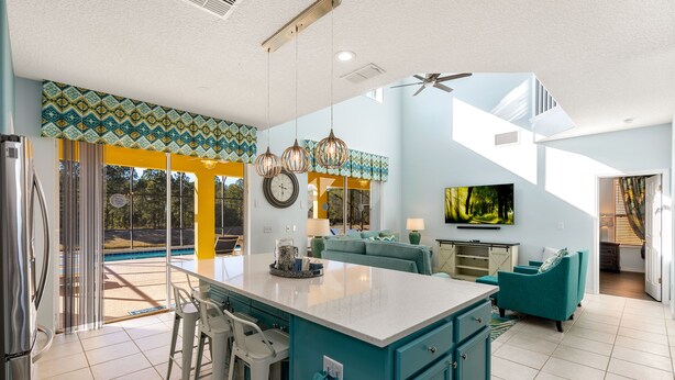 Una cocina amplia con una isla grande, taburetes de bar y vistas a una piscina.