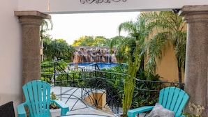Une terrasse avec des chaises turquoise, une petite piscine et une vue sur une cascade.