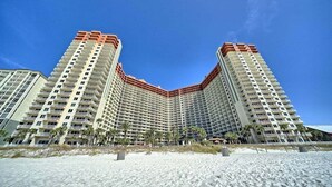 Un hotel moderno de altura con fachada curva, varios balcones y vista al mar.