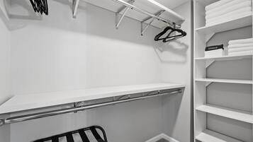 A walk-in closet with open shelving, a hanging rod, and a bench.
