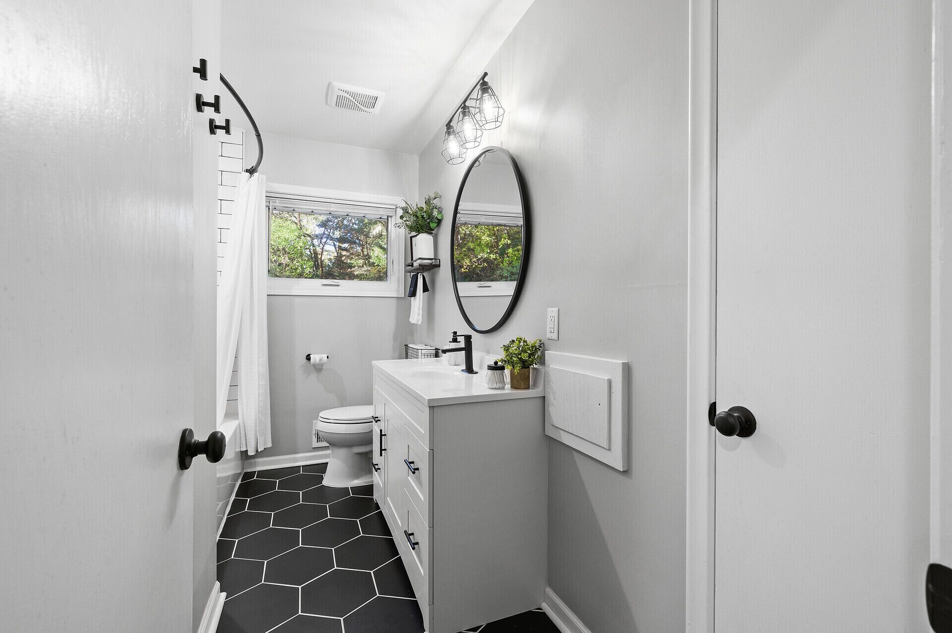 A bathroom with a toilet, sink, mirror, and shower.