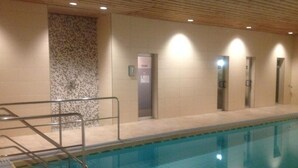 An indoor swimming pool with tiled walls, a wooden ceiling, and a tiled floor. - One-room vacation apartment in vacation park with swimming pool (Missen-Wilhams)