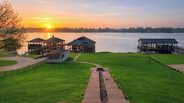 A lakeside property with a gazebo, a covered pavilion, and a pathway leading to a dock. - Beautiful False River Home on water w/ Dock (New Roads)